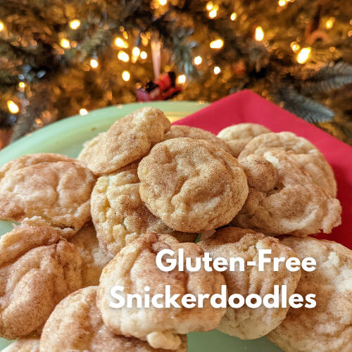 Pile of gluten-free snickerdoodles coated in cinnamon sugar on a plate by warm lights.