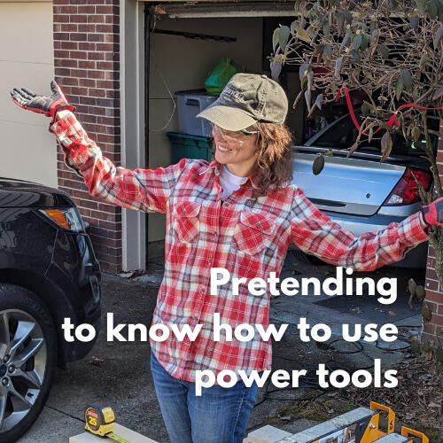 Jojo in a plaid shirt and cap, arms out, smiling near the garage with tools in the background.